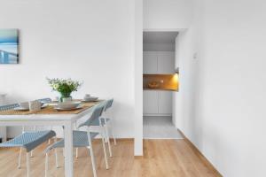 ein Esszimmer mit einem weißen Tisch und Stühlen in der Unterkunft Ivory Nature & Beachside by Elite Apartments in Przymorze