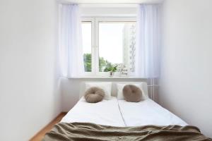 ein weißes Bett mit zwei Kissen in einem Zimmer mit einem Fenster in der Unterkunft Ivory Nature & Beachside by Elite Apartments in Przymorze