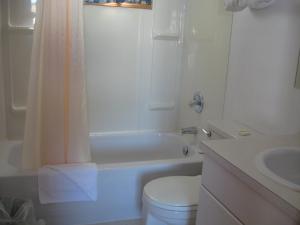 a bathroom with a toilet and a tub and a sink at Pals Motel and RV Park in Medicine Hat +17 photos