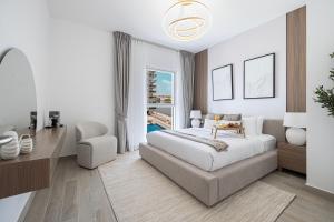 a bedroom with a bed and a chair and a window at DVH Luxe Retreats 2BR Yas Island by Ferrari World & Yas Mall in Abu Dhabi