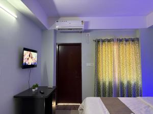 a bedroom with a bed and a tv on a wall at DXK Villa Homestay in Guwahati