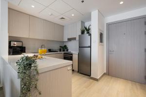 a kitchen with white cabinets and a black refrigerator at DVH Luxe Retreats 2BR Yas Island by Ferrari World & Yas Mall in Abu Dhabi +60 photos