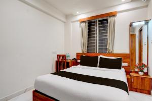 a bedroom with a large bed and a window at Super Townhouse Marathahalli KLM Fashion Mall Formerly Hotel Avenue in Bengaluru