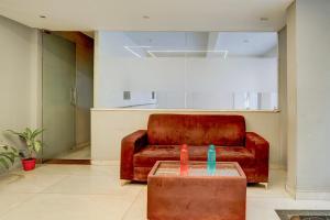 a brown leather couch in a living room with two candles at Super Townhouse Marathahalli KLM Fashion Mall Formerly Hotel Avenue in Bengaluru