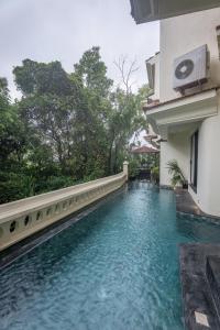 a swimming pool outside of a building with blue water at Morii Homes 4BHK Villa with private pool Parra, Assagao in Parra