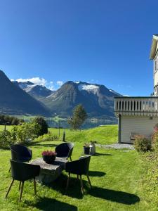 a patio with chairs and a table with mountains in the background at Vollsnes Feriehus in Hjelle