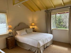 a bedroom with a bed with two lamps and two windows at Orchard Homestead Countryside Retreat in Yallingup Siding