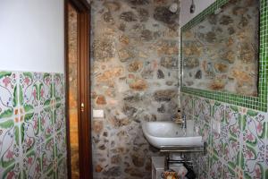 a bathroom with a sink and a stone wall at La Casa del Geko in Cefalù