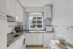 eine Küche mit weißen Schränken und einer Spüle und einem Fenster in der Unterkunft Apartamento en Vejer in Vejer de la Frontera