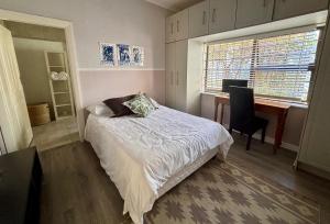 Un dormitorio con una cama y un escritorio con una computadora. en Bottle brush Fishhoek, en Fish Hoek