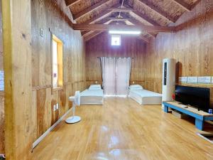 a room with wooden walls and wooden floors and a television at Udo Sunflower Pension in Yŏngil-tong