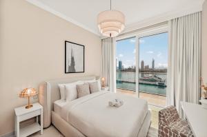 une chambre blanche avec un lit et une grande fenêtre dans l'établissement Luxury 2BR Retreat Gorgeous Beach & Skyline Views, à Dubaï 74 autres photos