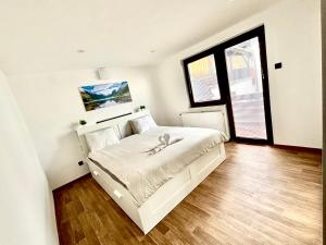 a bedroom with a large white bed with a wooden floor at M&M apartma in Bohinj