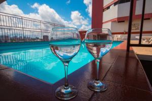 two wine glasses sitting on a table next to a swimming pool at GoldMen Business Manaus - Taj Mahal in Manaus