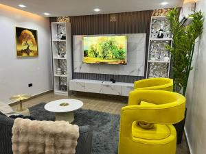 a living room with yellow chairs and a flat screen tv at Luxury Homes in Lekki