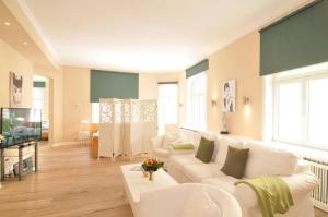 ein Wohnzimmer mit weißen Sofas und einem TV in der Unterkunft Café Orth in Westerland