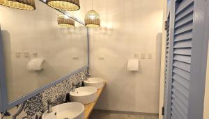 a bathroom with three sinks and two mirrors at Blau Hostel in El Nido