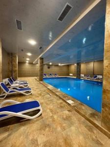 a large swimming pool with blue water and blue chairs at Alvina complex Vakas Tsakghadzor apartament in Tsaghkadzor
