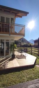 a house with a deck with the sun in the background at Family Apartment Sonja Terrace & mountain view in Rauris