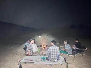 un gruppo di persone seduti intorno al fuoco sulla spiaggia di Farm house , jaisalmer a Jaisalmer
