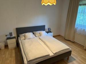 a bedroom with a bed with white sheets and a chandelier at Gästehaus Barbara in Gablitz