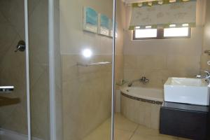 a bathroom with a shower and a sink and a tub at Hotel Aguia Negra in Vilanculos +33 photos
