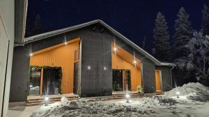a building with snow in front of it at night at Villa Arctic Trail B - Lapland Escape with Outdoor Hot Tub & Ylläs Ski Passes in Äkäslompolo