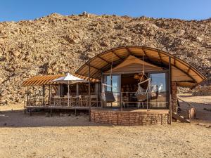 a building with chairs and umbrellas in the desert at Camp Sossus in Sesriem