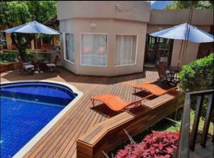 a deck with a pool and chairs and an umbrella at Chale Penedo no Centro com Piscina,Hidro e Sauna ! in Itatiaia