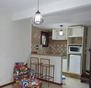 a kitchen with a counter and a chair in a room at Chale Penedo no Centro com Piscina,Hidro e Sauna ! in Itatiaia