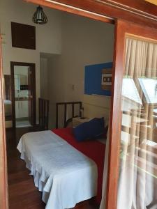 a bedroom with a bed with a red and white blanket at Chale Penedo no Centro com Piscina,Hidro e Sauna ! in Itatiaia