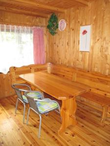 a dining room with a wooden table and two chairs at Domek nad jeziorem in Kretowiny