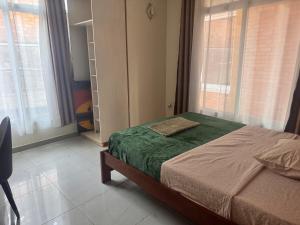 a bedroom with a bed with a green blanket at Family Corner Suite by Iwacu Stays in Kigali