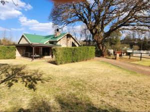 une maison avec un toit vert et une grande cour dans l'établissement Big Oak Cottages, à Dullstroom