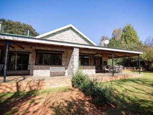 une maison en pierre avec un porche et un patio dans l'établissement Big Oak Cottages, à Dullstroom