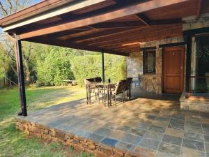un patio avec une table et des chaises sous un pavillon dans l'établissement Big Oak Cottages, à Dullstroom 6 autres photos