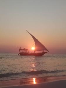 un barco en el océano con la puesta de sol en el fondo en Nashipai house, en Nungwi