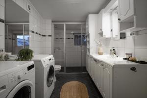a white bathroom with a washing machine and a sink at Tromsø Terrace - Top floor apartment with amazing views in Tromsø