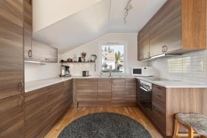a kitchen with wooden cabinets and a window at Tromsø Terrace - Top floor apartment with amazing views in Tromsø