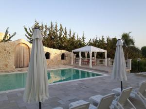 a swimming pool with two umbrellas and a gazebo at Casale Rocca Russa B&B in Villaggio Mosè