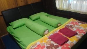 a bed with green sheets and pillows on it at The Norsyah Villa selayar in Pareangang +7 photos
