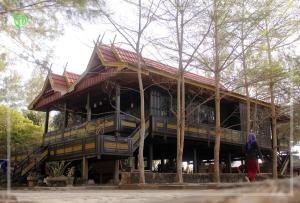 a large wooden building with stairs in front of trees at The Norsyah Villa selayar in Pareangang