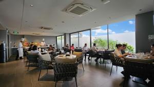 JBAY Beachfront Boutique Hotel في دا نانغ: مجموعة من الأشخاص يجلسون على الطاولات في مطعم