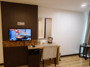 a room with a table and a tv on a wall at Classy Studio Apartment (KBCP) in Kota Bharu