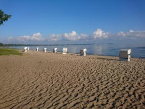 a row of chairs on a sandy beach near the water at Ostseewohnung Weiße Wiek in Hohenkirchen