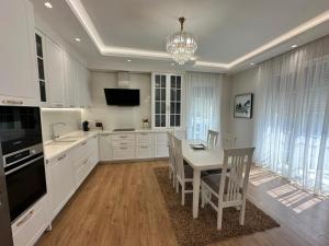 a kitchen with white cabinets and a table and chairs at Vila Mullaj in Durrës