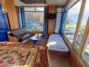 a room with a bed and a chair and a window at Hotel Pandey Lodge By StayApart in Munsyari