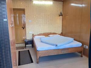 a bedroom with a wooden bed with white sheets at Hotel Pandey Lodge By StayApart in Munsyari