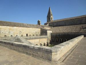 an old stone building with a tower in the background at Logis Hostellerie De L'Abbaye in Le Thoronet