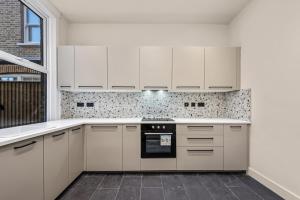 a kitchen with white cabinets and an oven at Beautifully Designed Studio with Communal Full Kitchen - Full Access in London